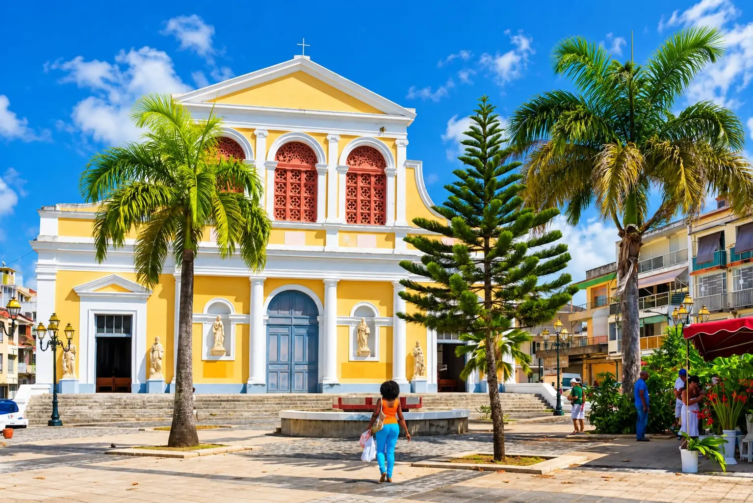Yellow façade of the Saint-Pierre-et-Saint-Paul cathedral in Pointe-à-Pitre, under palm trees